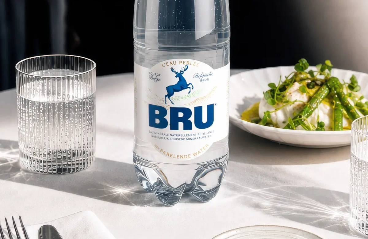 Бутылка BRU на ресторанном столе рядом с бокалом и блюдом